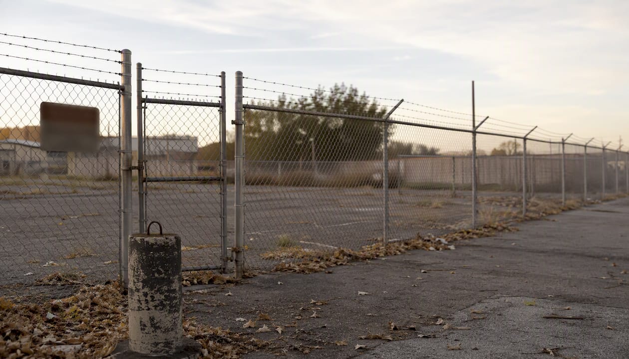 Chain-link fence with barbed wire at vacant property