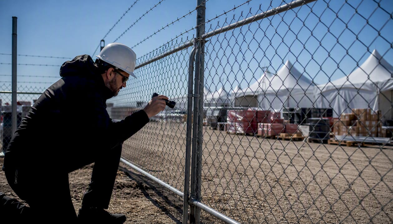 Security professional inspecting venue fence during risk assessment