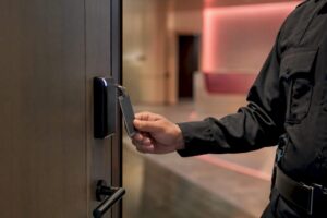 Close-up hand holding security badge to door reader