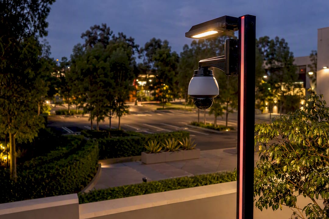Security camera on pole overlooking landscaped parking lot