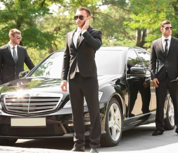 Handsome bodyguards near car outdoors