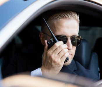 Man Sitting Inside Car Doing Surveillance Talking On Walkie Talkie