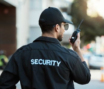 Radio, man and a security guard or safety officer outdoor on a city road for communication. Back of a person with a walkie talkie on urban street to report crime for investigation and surveillance